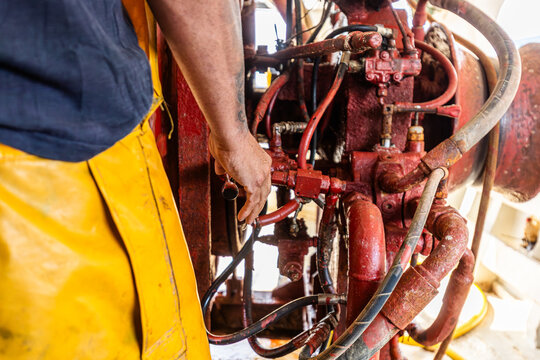 Fisherman in yellow gear working on boat engine