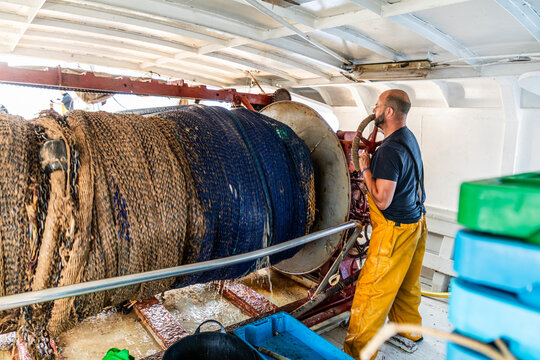 Fisherman hauling net on trawler winch during fishing