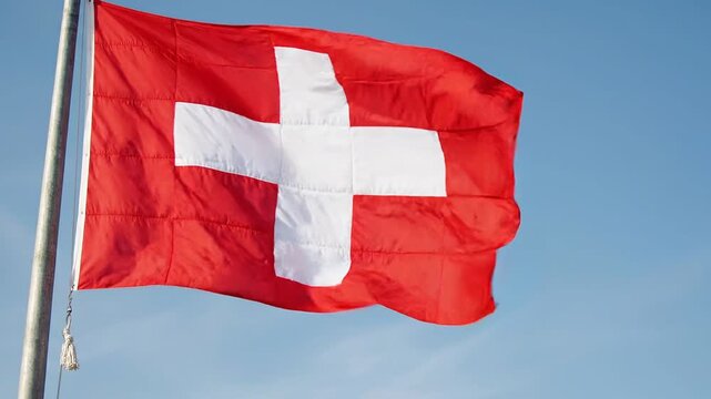 Swiss flag waving against a clear blue sky