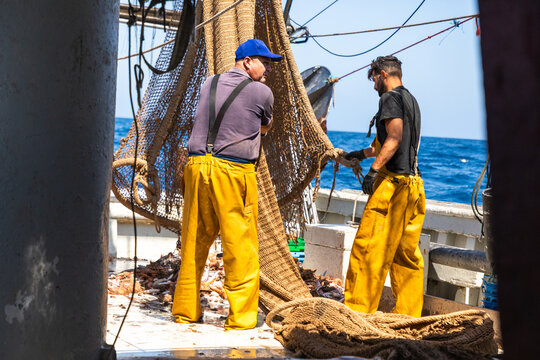 Fishermen hauling heavy net on deck during open sea work
