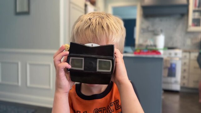 Young boy looking through a vintage handheld stereoscope 3D viewer at home. Nostalgic childhood toy and classic stereoscopic viewer evoke retro memories and analog entertainment. 15249
