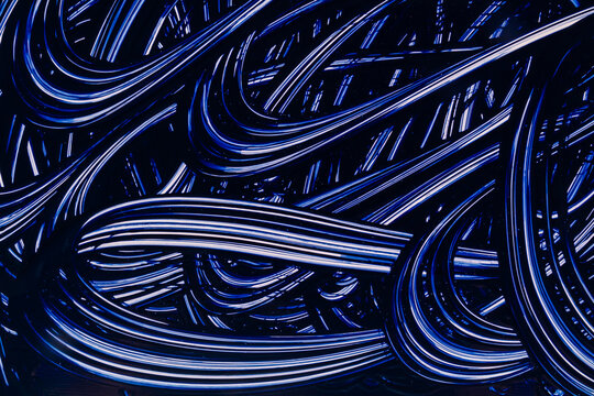 Abstract blue neon light trails on glossy black surface