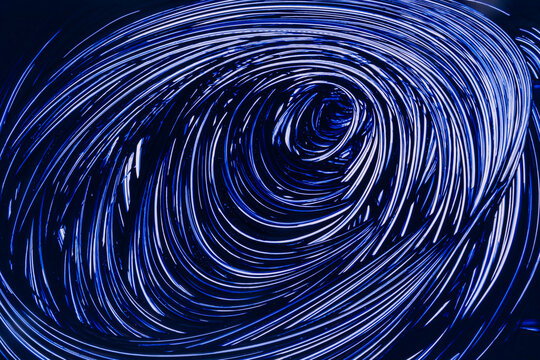Abstract blue light swirl forming futuristic vortex tunnel