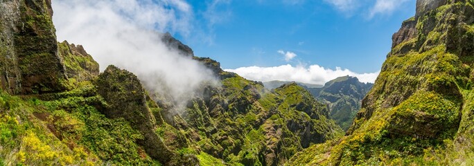 Obraz premium Green volcanic ridges and deep valley in clouds