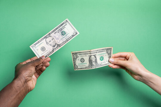 Multiethnic hands exchanging US dollar banknotes on green