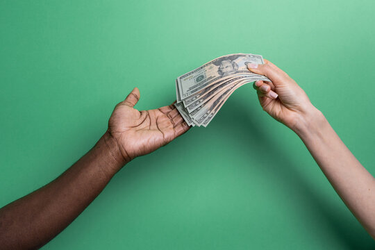 Multiethnic hands exchanging cash on green backdrop