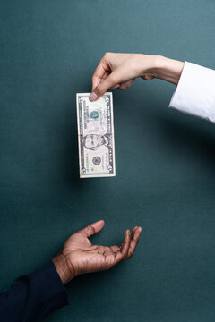 Multiethnic hand exchange with US dollar banknote on green