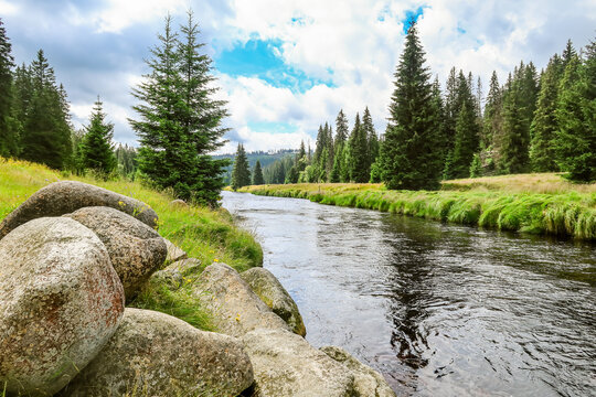 Calm river with granite boulders in spruce forest