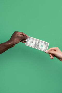 Multiethnic hands exchanging one dollar bill on green