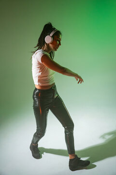 Woman dancer in headphones performing in green studio light