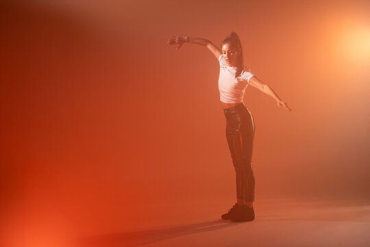 Woman dancer posing in orange studio haze with backlight