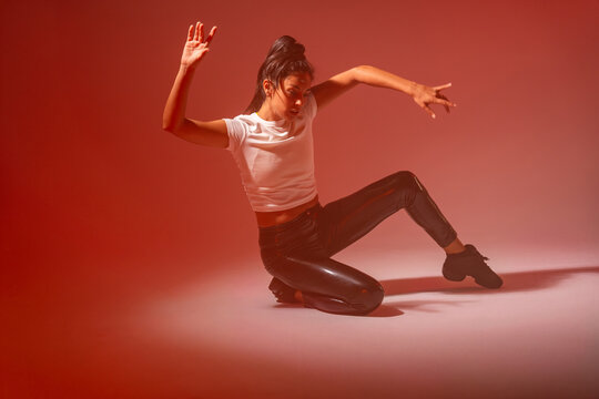 Woman dancer in modern pose under red studio lighting