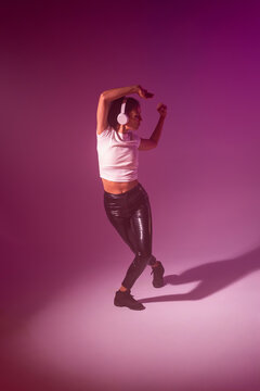 Woman dancer with headphone in neon studio background