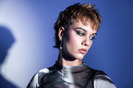 Young woman fashion model posing in studio with blue light