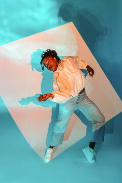 Afro woman dancer striking pose in blue studio light