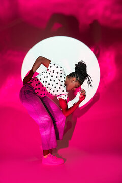Afro woman dancer posing in neon pink studio light