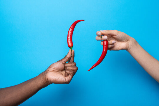 Multiethnic hands holding red chili pepper on blue
