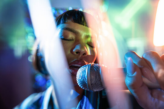 Young Latin woman singer performing live with microphone
