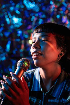 Young Latin woman singer performing with mic on stage