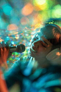 Young Latin woman singer recording with headphones and mic
