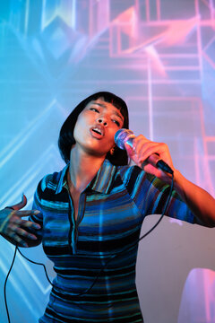 Young Latin woman singer performing with neon stage light