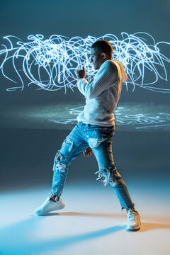 Urban dancer posing in studio with abstract light painting