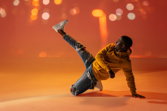 Black man performing breakdance move in urban night