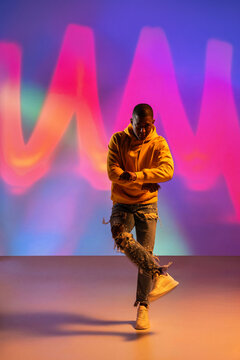 Black man urban dancer performing under colorful neon lights