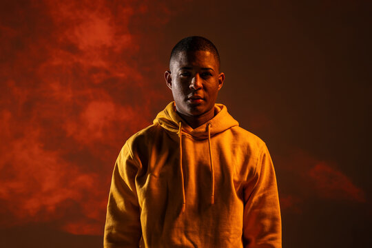 Black man urban dancer portrait in hoodie with red smoke