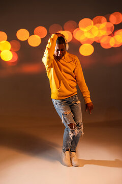 Urban dancer in yellow hoodie posing with headphone bokeh