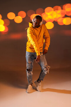 Black man urban dancer in hoodie with headphones at night