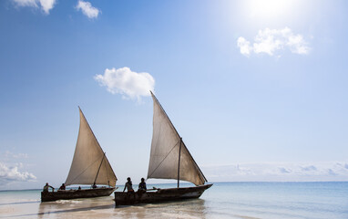 Tradycyjne drewniane łodzie z białymi żaglami na plaży Zanzibaru Tanzania © kubikactive