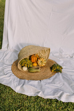 Autumn gourds in a woven straw bag on white fabric