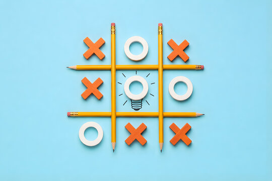 Tic tac toe board created with yellow pencils featuring orange Xs white Os and glowing lightbulb at center on blue background