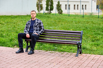 Obraz premium Young man sits calmly on park bench