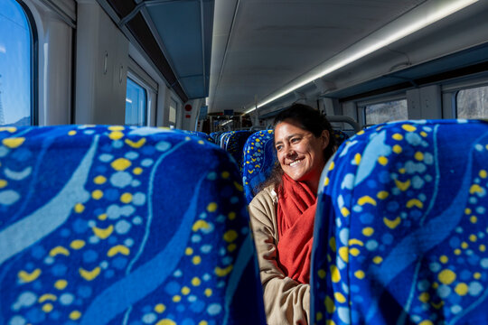 Woman enjoying quiet train ride between blue seats