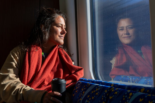 Woman with red scarf looking out train window at night