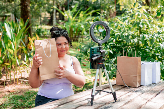 Influencer filming product unboxing with ring light outdoors