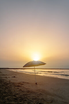 Vertical straw beach umbrella with warm morning sunlight