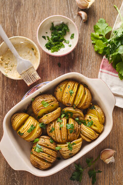 Hasselback roasted potato in baking dish with herb butter