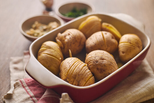 Raw Hasselback potatoes in a red ceramic baking dish ready for cooking