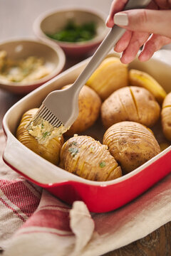 Hasselback roasted potato in baking dish with herb butter