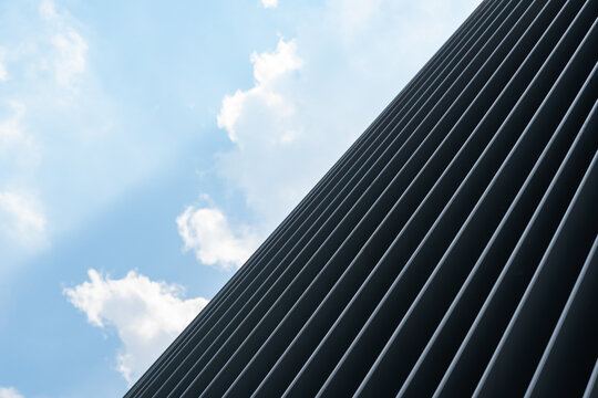 Modern facade detail against blue sky with soft cloud