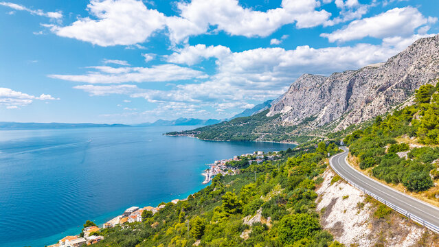 Aerial view of the scenic coastal road along the Adriatic Sea in Croatia with mountains and Mediterranean village