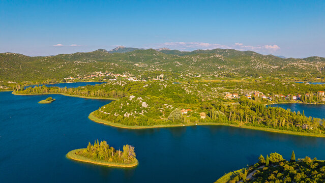 Aerial view of Bacina Lakes in Dalmatia, Croatia, featuring small islands, lush green hills, and blue water under a clear summer sky