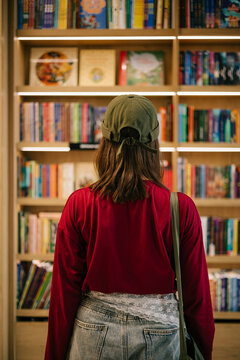 Person browsing bookshelves in a cozy bookstore interior