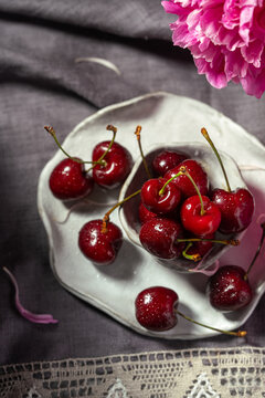 Fresh cherries on white ceramic plate with pink peony