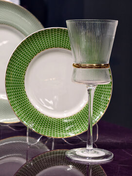 Single crystal glass in focus with green plates behind on an elegant dining setup