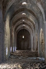 Obraz premium Interior view of a dark ruined ancient stone building with arched ceiling and light shafts
