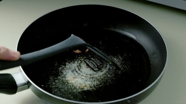 Close-Up of Worn Nonstick Teflon Frying Pan Being Scrubbed with Kitchen Utensil, Illustrating Cookware Safety and Potential Health Risks, 4K 60fps